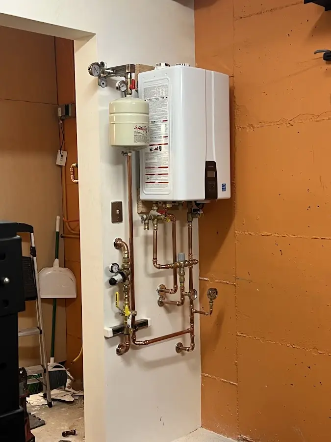 Plumbing technician inspecting water heater connections in Honey Brook